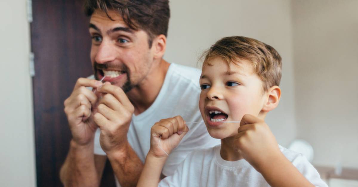 Adult-and-child-in-white-tees-brushing-teeth-together