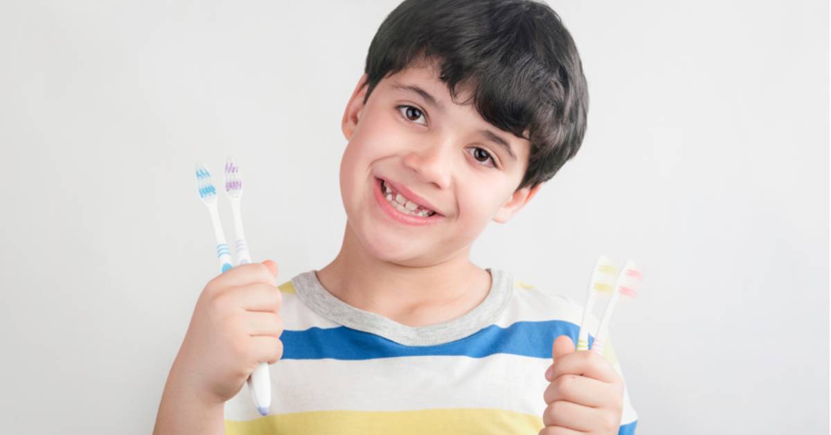 Child-holding-multiple-toothbrushes-against-a-white-background