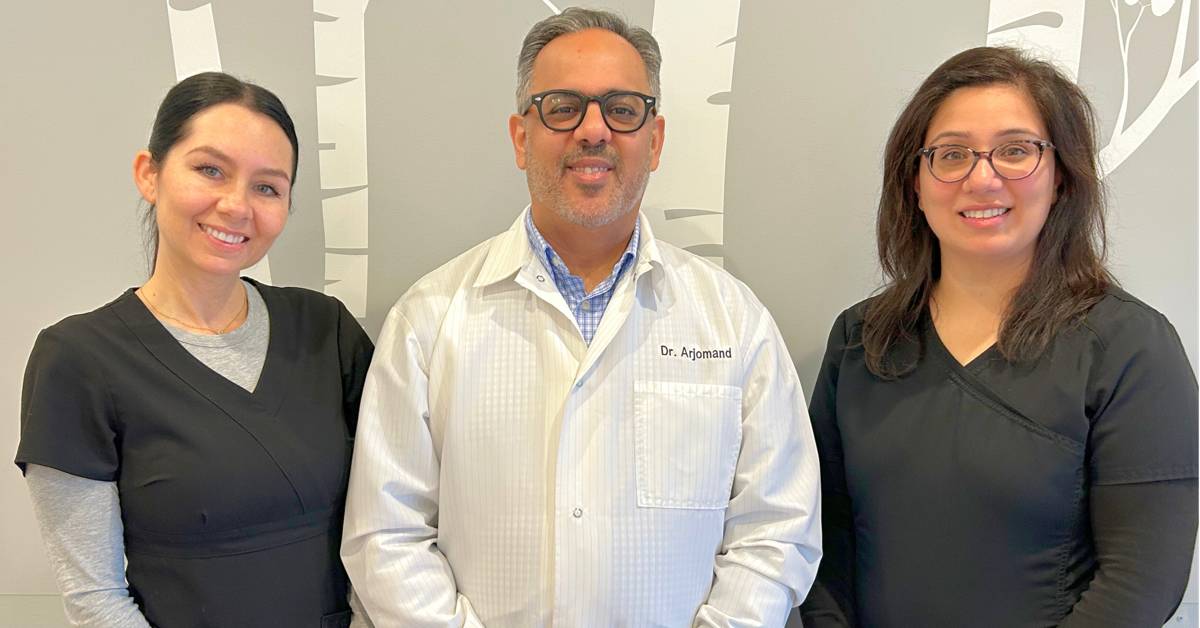 Three-medical-staff-members-in-uniforms-posing-in-an-office-with-a-patterned-wall
