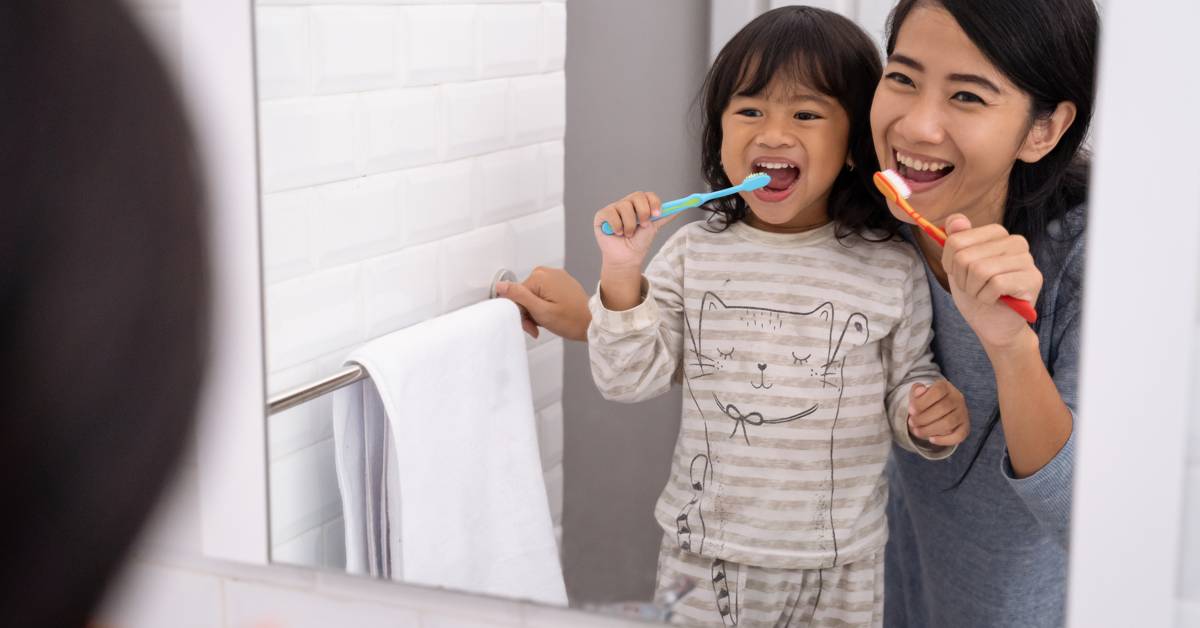 Two-people-brushing-teeth-in-front-of-a-bathroom-mirror