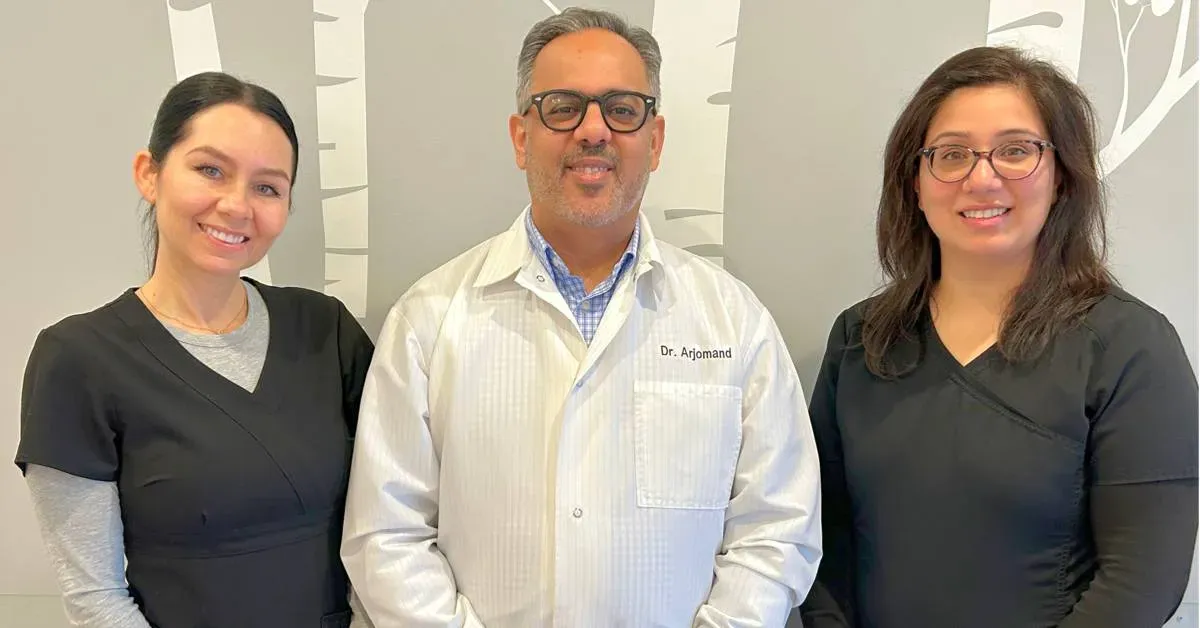 Three-medical-staff-members-in-uniforms-posing-in-an-office-with-a-patterned-wall