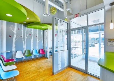 A bright, colorful pediatric dental clinic waiting room with playful decor and kid-friendly seating.